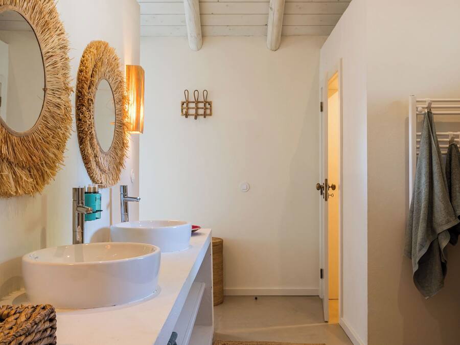 Un baño moderno con dos lavamanos, un espejo grande y techo de madera.