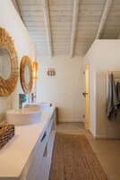 A modern bathroom with two sinks, a large mirror, and a wooden ceiling.