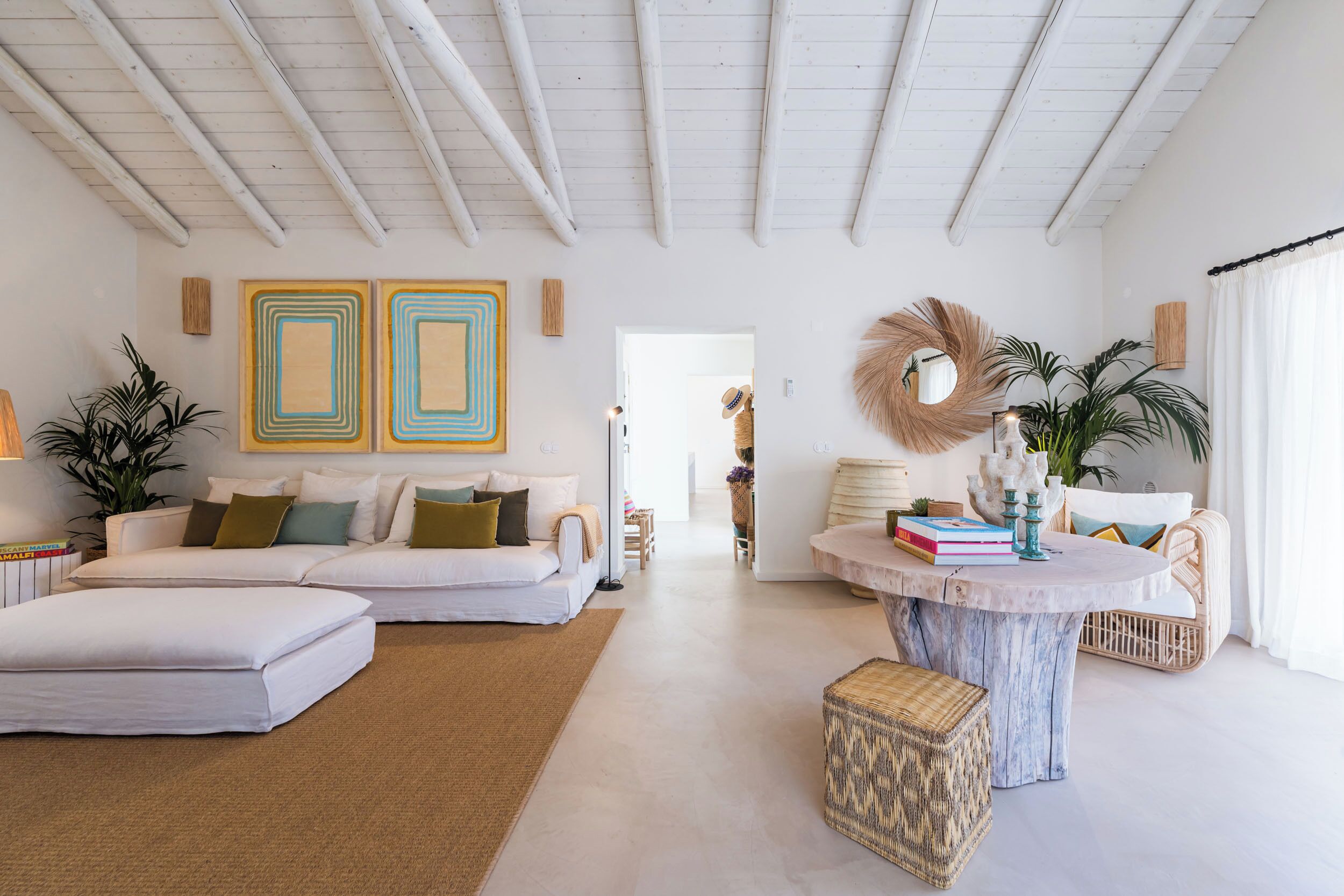 A spacious living room with a white sofa, a round coffee table, and a large mirror.