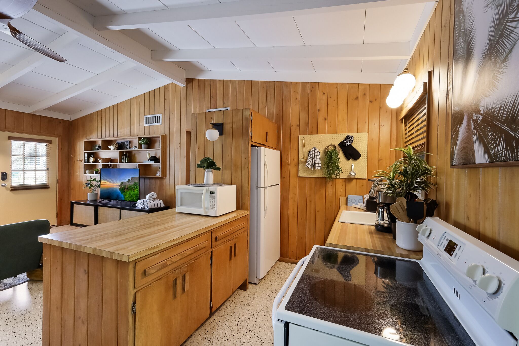 A compact kitchen with wooden cabinets, a microwave, a refrigerator, and a stove.