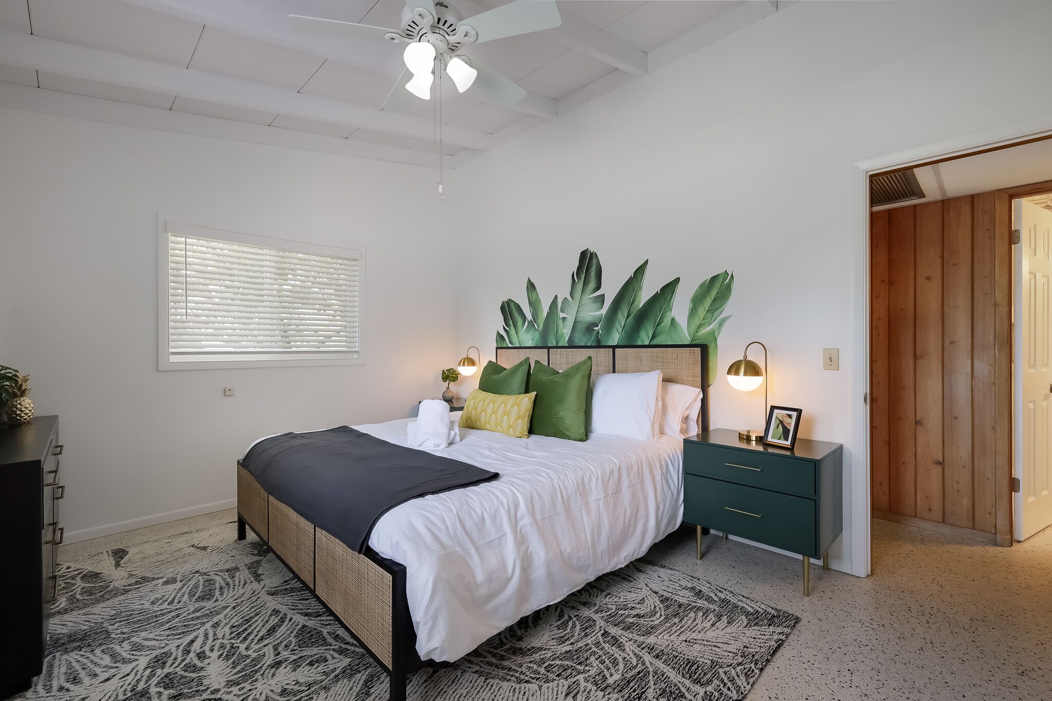 A bedroom with a bed, bedside table, and a large plant.