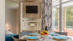 Un comedor moderno con una mesa redonda, sillas y un frutero. Un televisor está montado en la pared sobre la mesa.