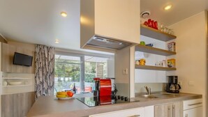 Una cocina moderna con un ventanal grande, armarios blancos y un horno empotrado.