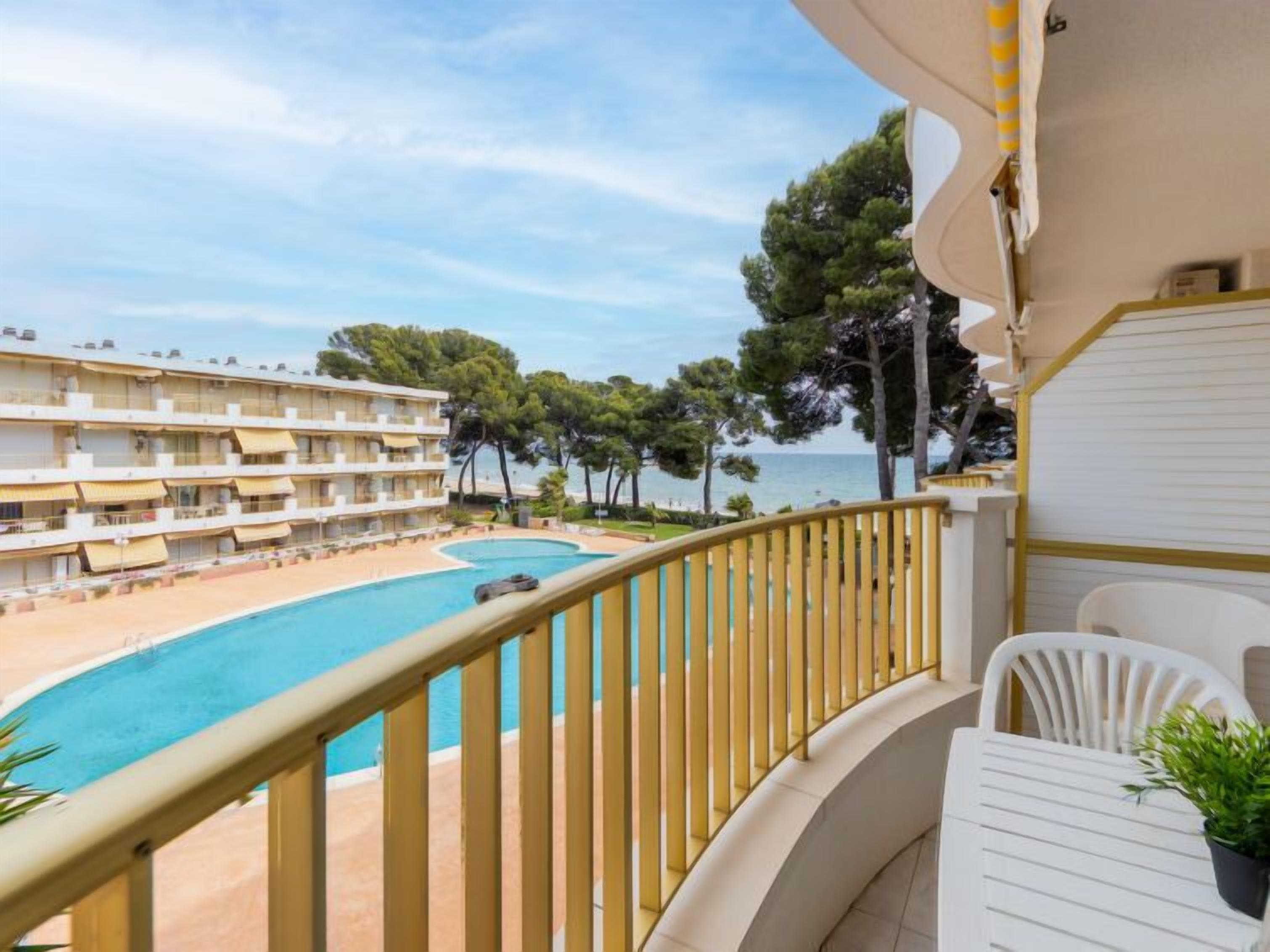 A balcony with a pool, overlooking a beach and a hotel building.