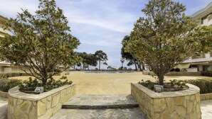A courtyard with a pool, surrounded by stone planters and trees. - International by Interhome (Cambrils)