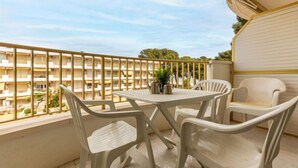 A balcony with a table and chairs, overlooking a building with multiple balconies. - International by Interhome (Cambrils)