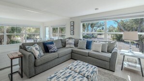 A spacious living room with a large gray sectional sofa, a wooden coffee table, and a patterned ottoman.