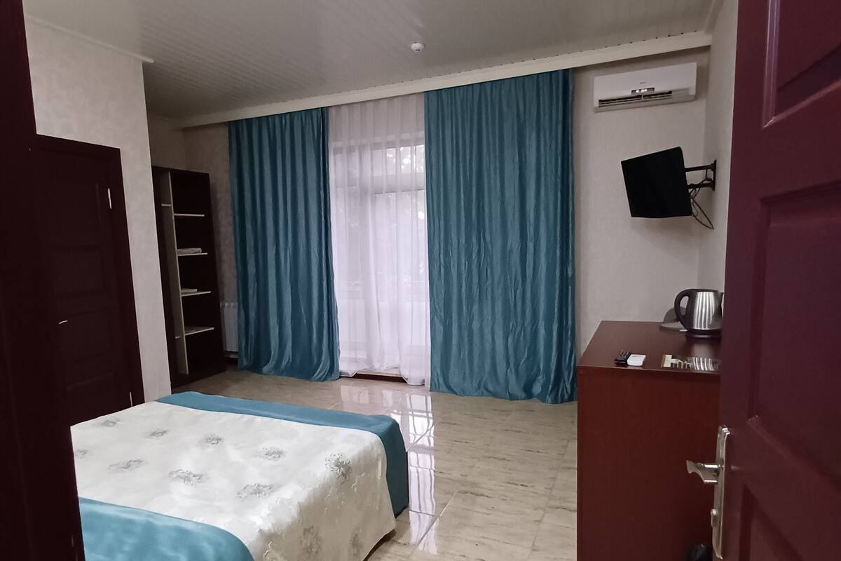 Una habitación de hotel con cama, escritorio, armario, televisión y aire acondicionado.