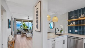 A modern kitchen with a large island, white cabinetry, and a view to the outdoors.