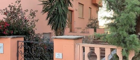 A building with a number 21 sign, a wrought iron gate, and a small balcony with a blue pot.