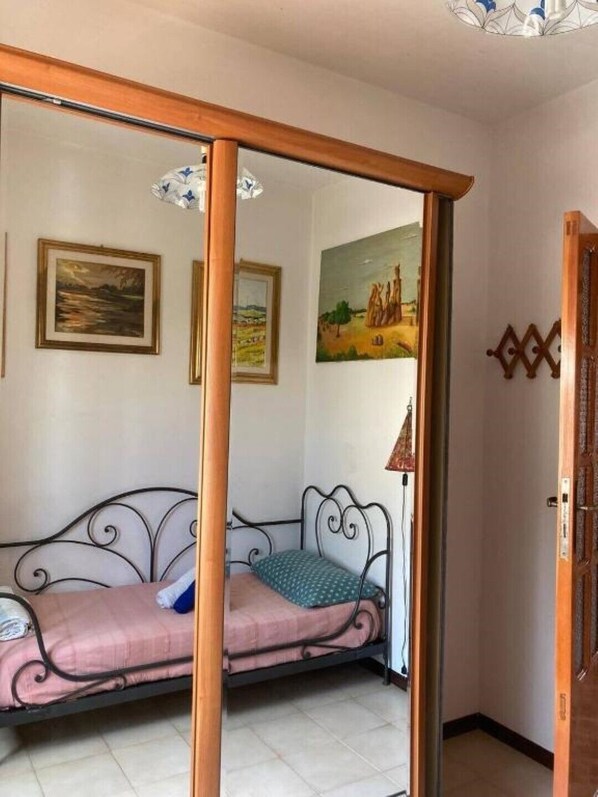 Une pièce avec un lit, une porte en bois et deux tableaux accrochés au mur.