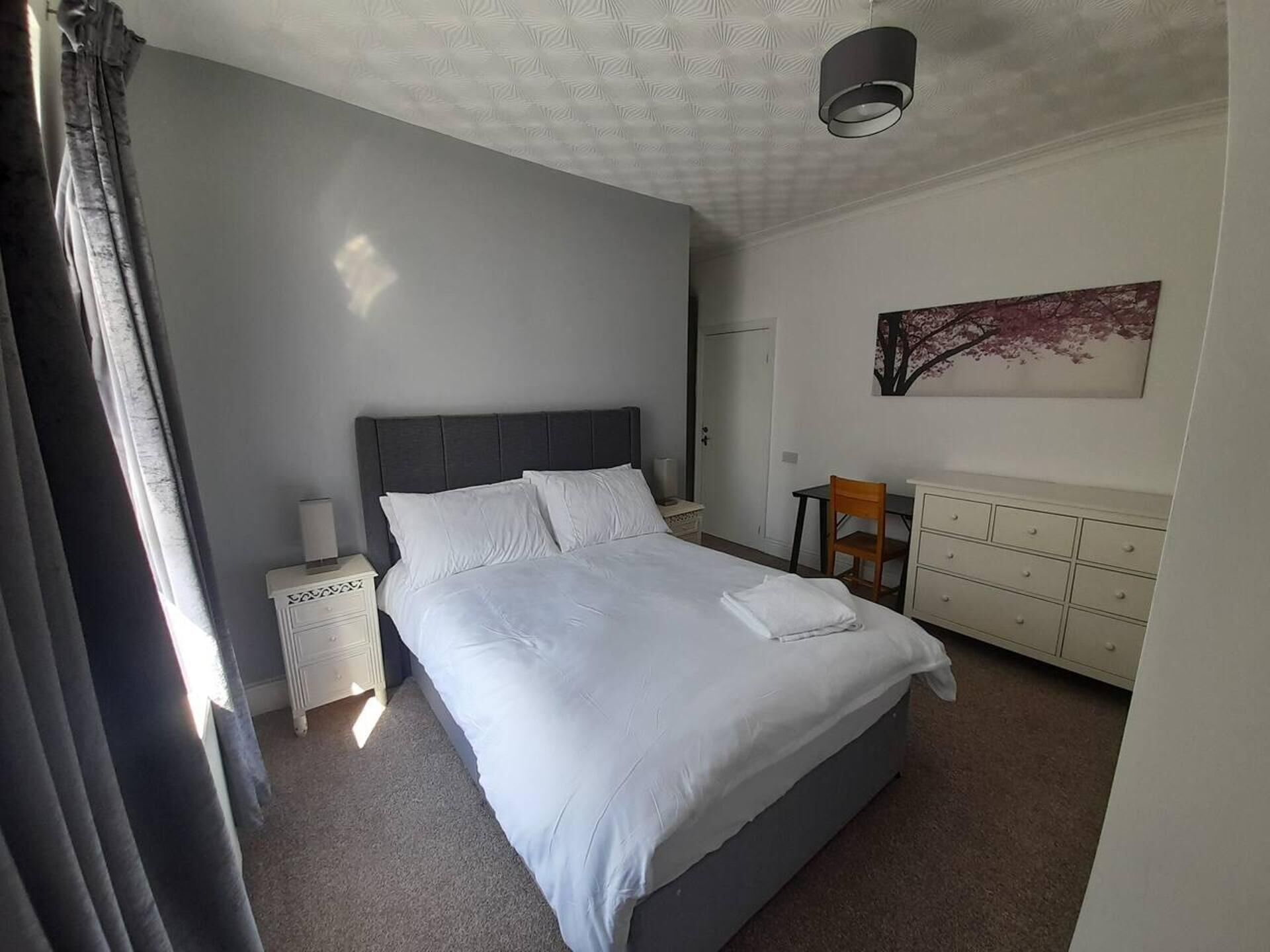 Une chambre à coucher avec un grand lit, une table de chevet, un bureau et une chaise.