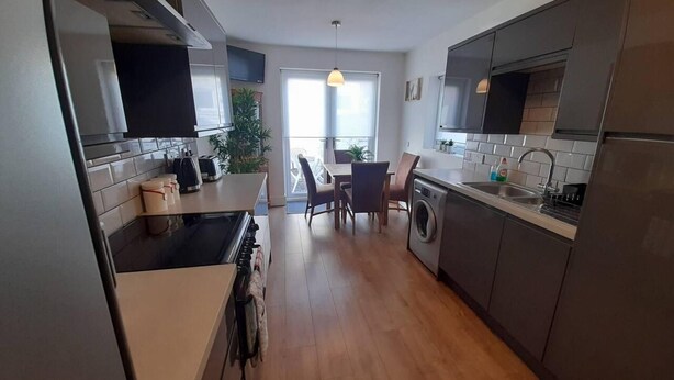 Een moderne keuken met een eethoek, houten vloeren en uitzicht.