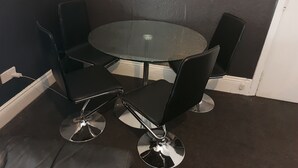 A corner seating area with a round glass table and four black chairs with chrome bases. - Family, Long Stay, Contractors, Stags and Hens (Newcastle-upon-Tyne)