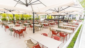 An outdoor dining area with multiple tables and chairs, covered by large umbrellas. - HOTEL RIVIERA (Constanta)