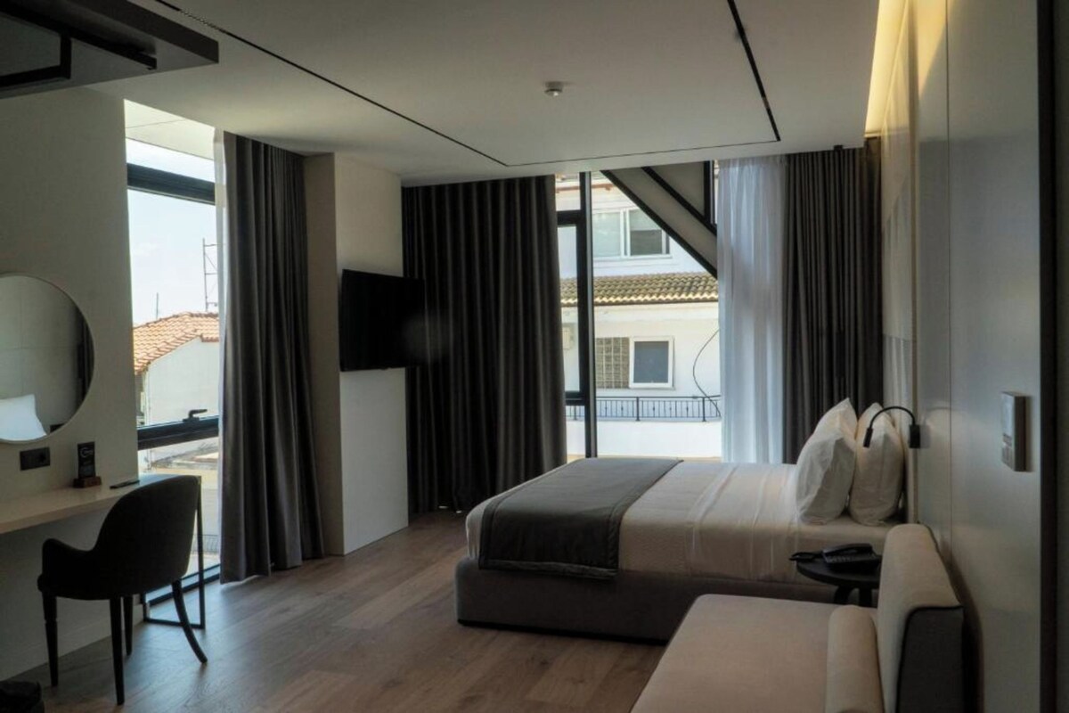 A modern hotel room with a large bed, a desk, and a TV.