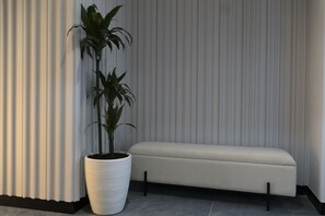 Un interior moderno con planta en maceta, un banco y persianas verticales.
