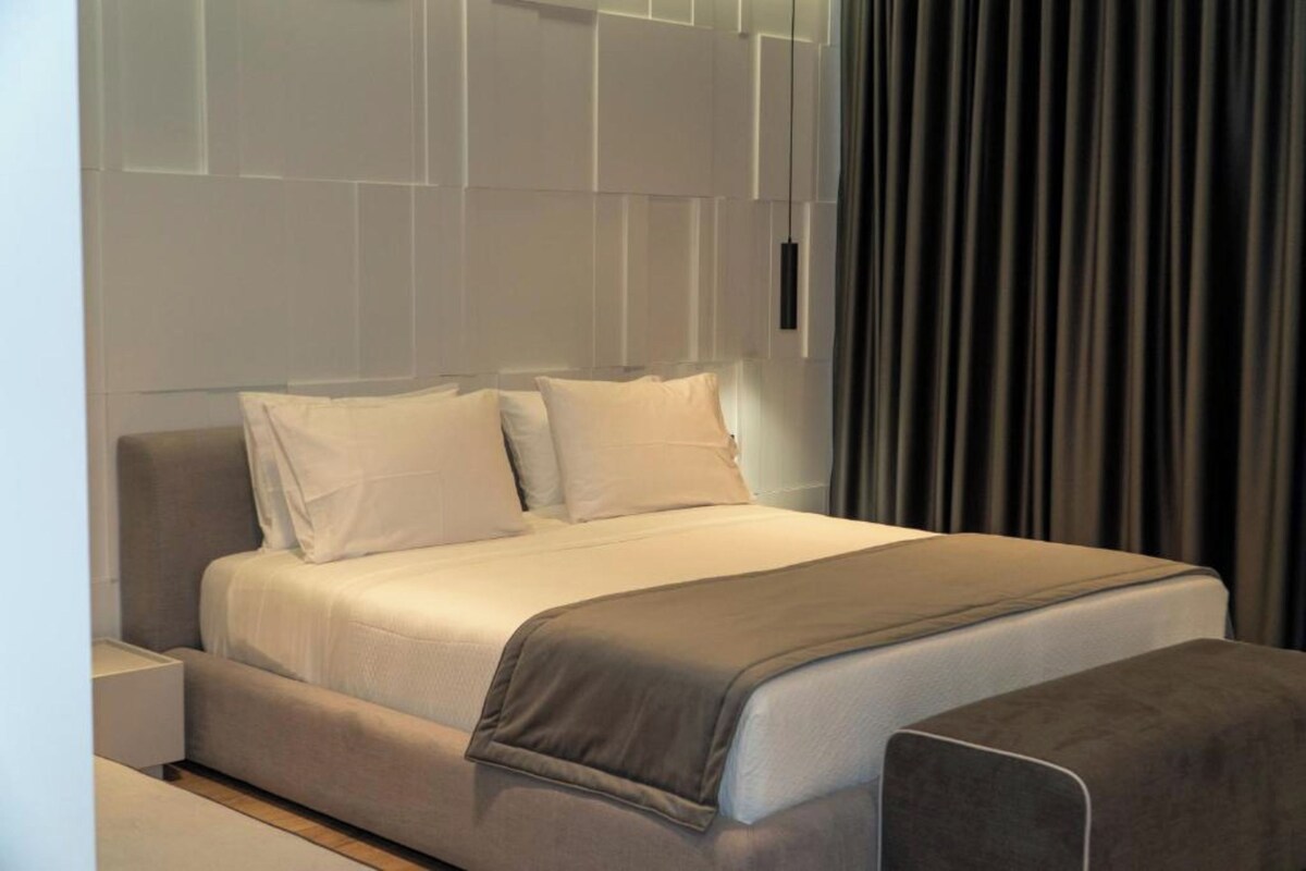 A modern hotel room with a large bed, a bedside table, and a curtain.