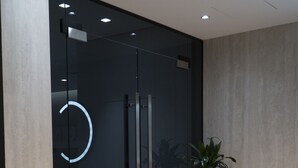 A modern interior with a glass door, a potted plant, and a concrete pillar. - Center Hotel (Sarandë)