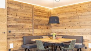 A modern dining area with a wooden wall panel design, a round table, and four chairs.