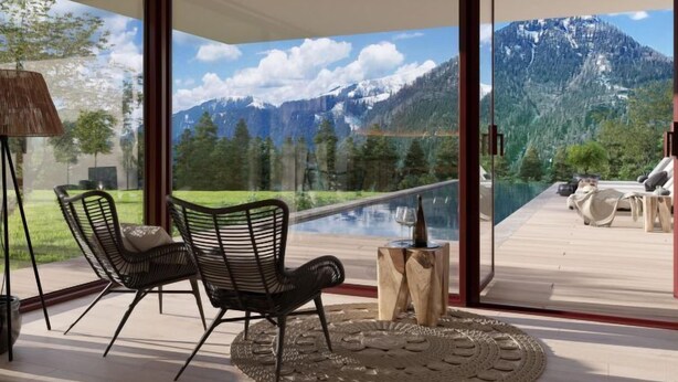 A modern room with a glass door leading to a balcony with a mountain view.