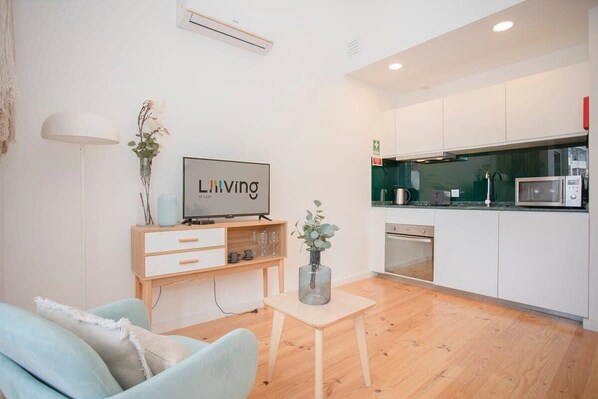 A modern living room with a TV, a small table with a vase, and a sofa.