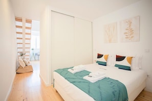 A bedroom with a bed, a wardrobe, and two wall-mounted artworks.