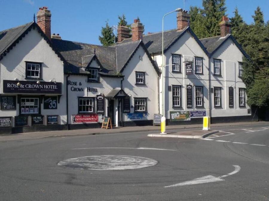 A traditional building with multiple signs for 'Rose & Crown Hotel' and 'Big' establishments.