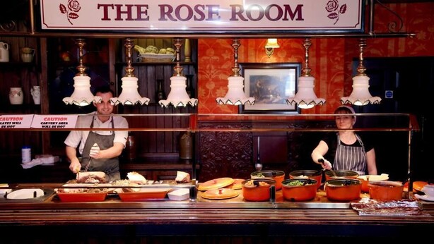 Een buffetbar met de naam 'The Rose Room', met meerdere stations en personeel dat gasten bedient.