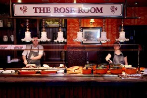 A buffet counter labeled "The Rose Room" with multiple food stations and staff serving.