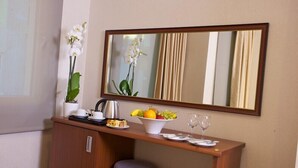 A hotel room with a wooden desk, a mirror, a potted orchid, a fruit bowl, a kettle, and a chair. - THE COACH HOTEL (Istanbul)