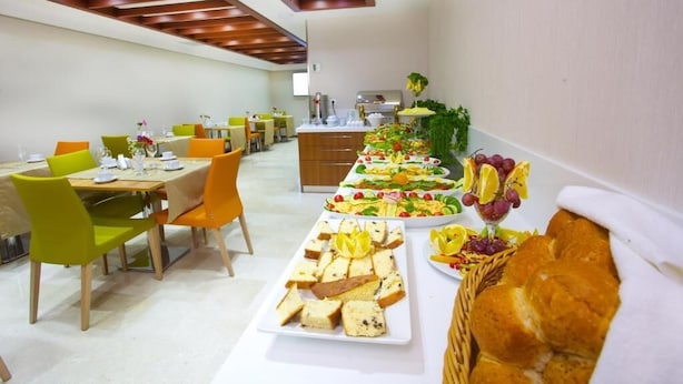 A dining area with multiple tables and chairs, a buffet with various food items, and a kitchen in the background. - THE COACH HOTEL (Istanbul)