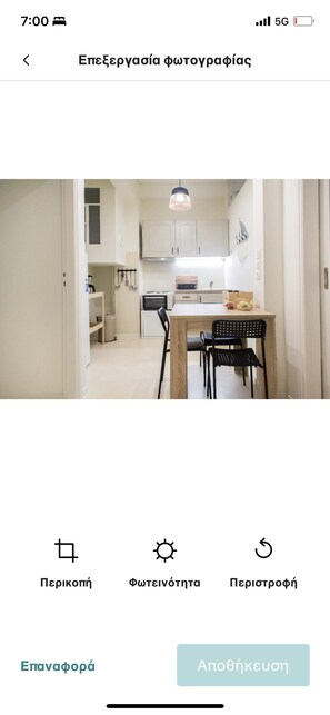 A modern kitchen with white cabinets, a wooden dining table, and black chairs. - Charming 1-bed Apartment Near Piraeus Port (Kallithea)