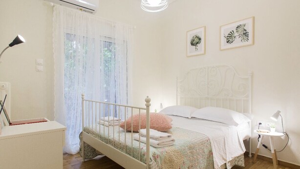 Une chambre à coucher comprenant un lit, un bureau, une chaise, un climatiseur et une fenêtre avec des rideaux.