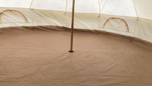 A tent with a central pole and a brown floor. - Woodlands Basic Bell Tent 2 (Grantham)