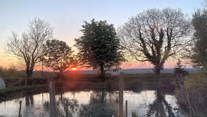 A serene landscape with a body of water, trees, and a sunset in the background. - Woodlands Basic Bell Tent 2 (Grantham)