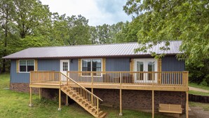 A two-story house with a wooden deck, a staircase, and a brick foundation. - Brand New Farmhouse Style Listing with views of the beautiful Spring River! (Mammoth Spring)