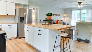 A modern kitchen with white cabinetry, a stainless steel refrigerator, a wooden countertop, and a bar stool. - Brand New Farmhouse Style Listing with views of the beautiful Spring River! (Mammoth Spring)