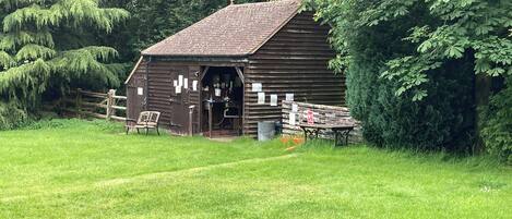 A rustic wooden barn with a sloped roof, a wooden door, and a small porch area.