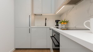 A modern kitchen with white cabinets, a black countertop, and a built-in coffee machine. - Boutiq Park Apartment Warsaw by Renters (Warsaw)