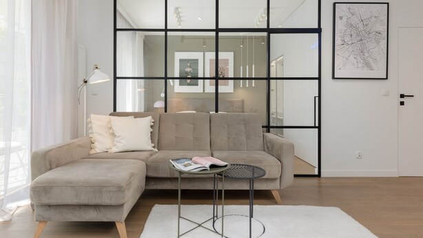 A modern living room with a sectional sofa, a small round table, and a white rug. - Boutiq Park Apartment Warsaw by Renters (Warsaw)