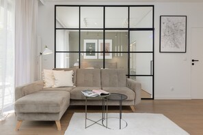 Relax in this stylish living room with a light-colored sofa, small table, and white rug.