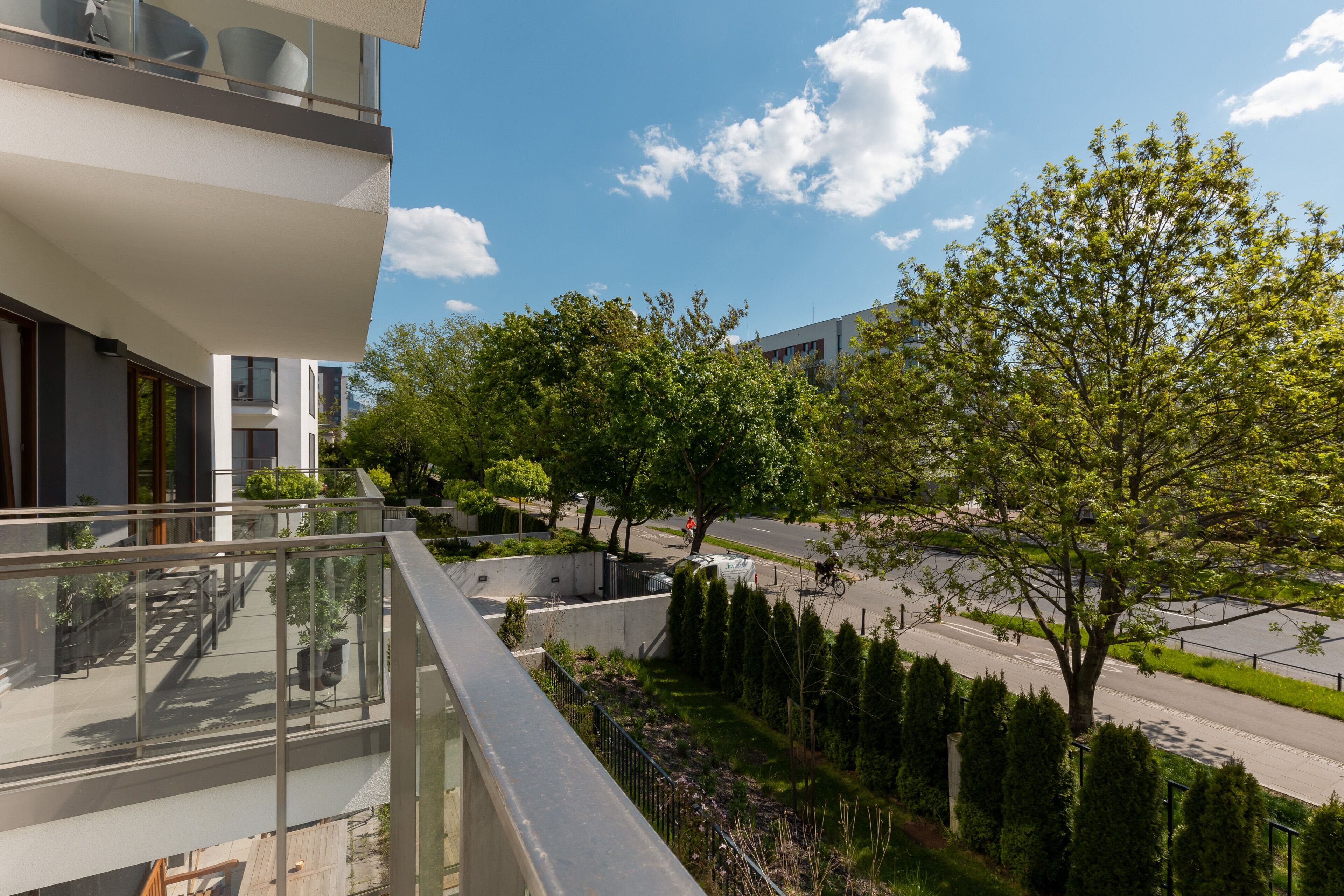 Ein modernes Gebäude mit einem Balkon mit Blick auf eine von Bäumen gesäumte Straße.
