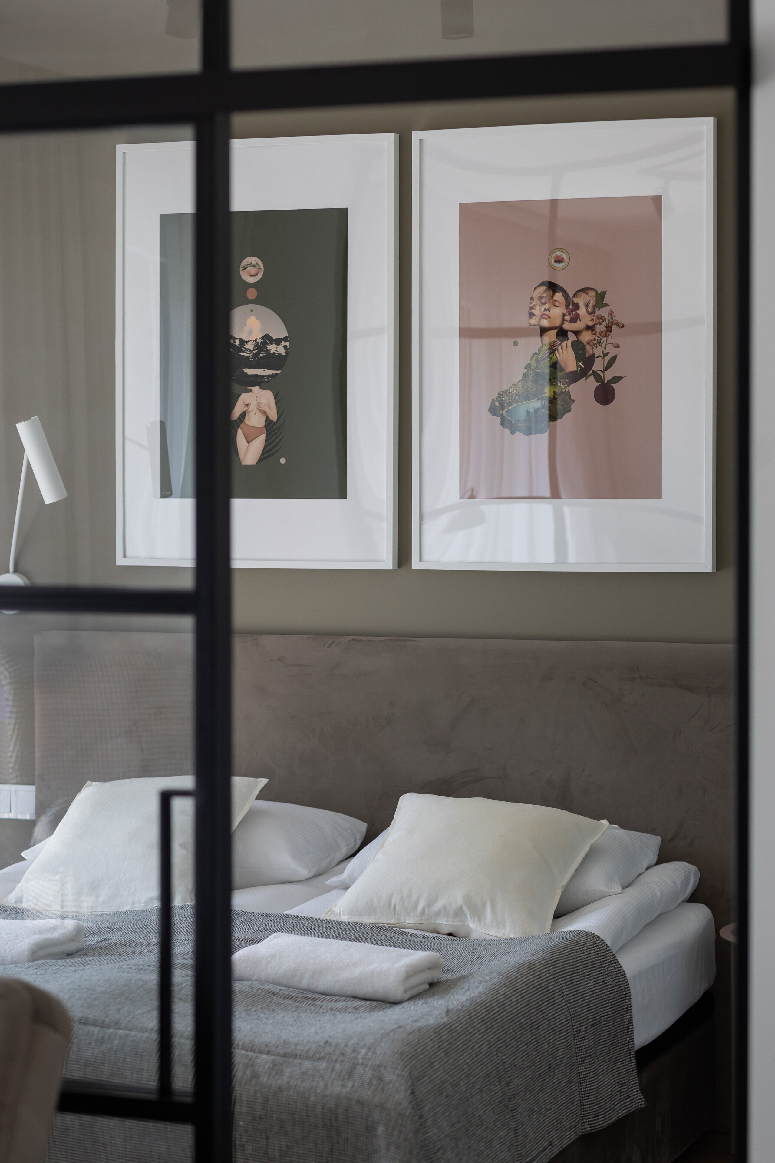 Un lit bien fait, avec une literie blanche et grise, une lampe de chevet et deux œuvres d’art encadrées accrochées au mur.