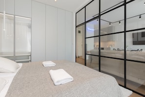 Experience the essence of Warsaw in this stylish room, featuring a large bed, glass partition, and modern kitchen.