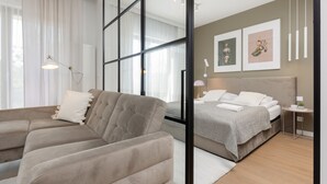 A modern bedroom with a sofa, a bed, and a bedside table. - Boutiq Park Apartment Warsaw by Renters (Warsaw)