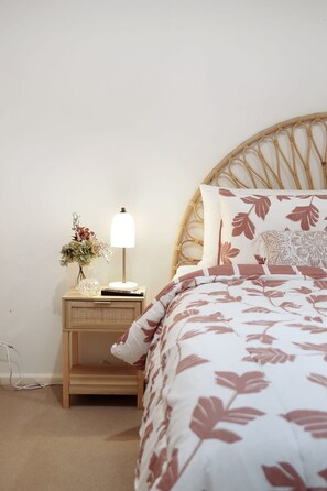 Ein Schlafzimmer mit einem Bett, einem Nachttisch mit Lampe und einem Wandregal.