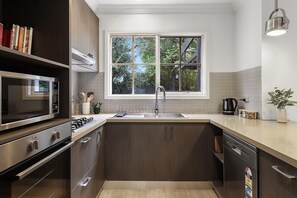 Een moderne keuken met een ingebouwde magnetron, kookplaat en vaatwasser.