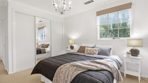 Un dormitorio con una cama grande, un armario, una ventana con vistas y una araña.