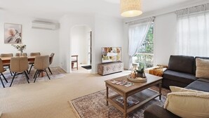 Una sala de estar con sofá, mesa de centro y comedor con sillas.